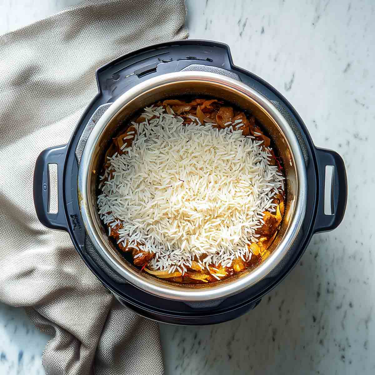 Uncooked basmati rice layered evenly over the lamb mixture in the Instant Pot.