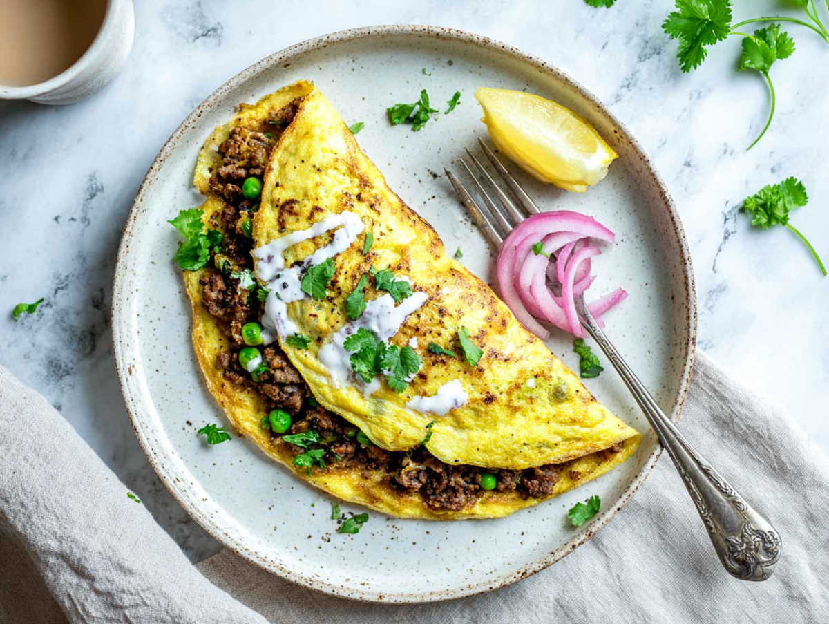 A folded omelet is filled with leftover lamb keema, peas, and yogurt drizzle.