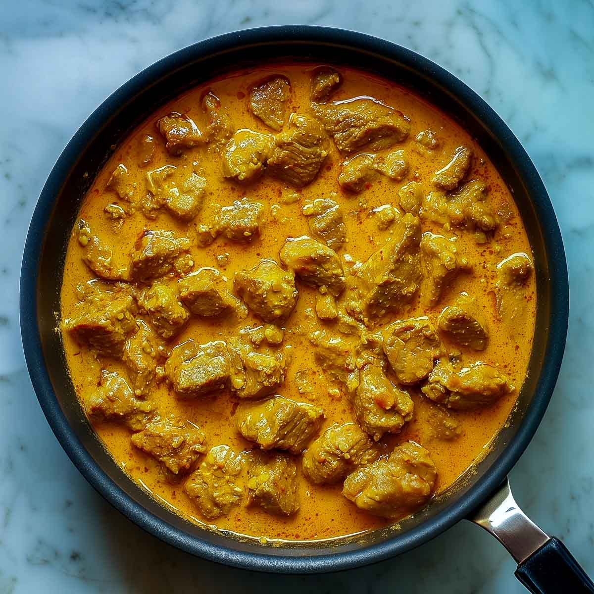 Lamb korma cooked down into a thick, creamy curry with a rich golden color.