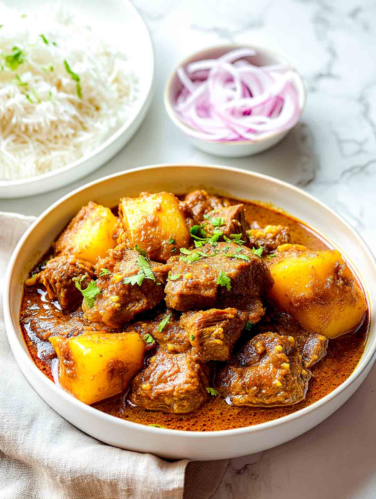 Side-angle view of lamb and potato curry showing thick gravy and tender meat.
