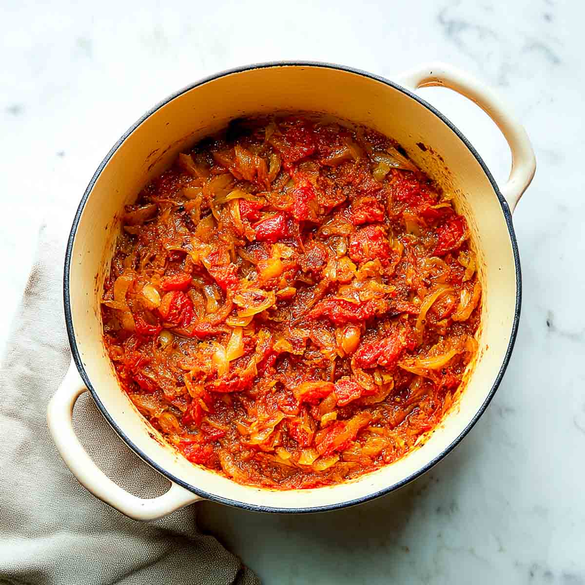 Cooked onions with tomatoes and spices simmering into a thick, red masala base.