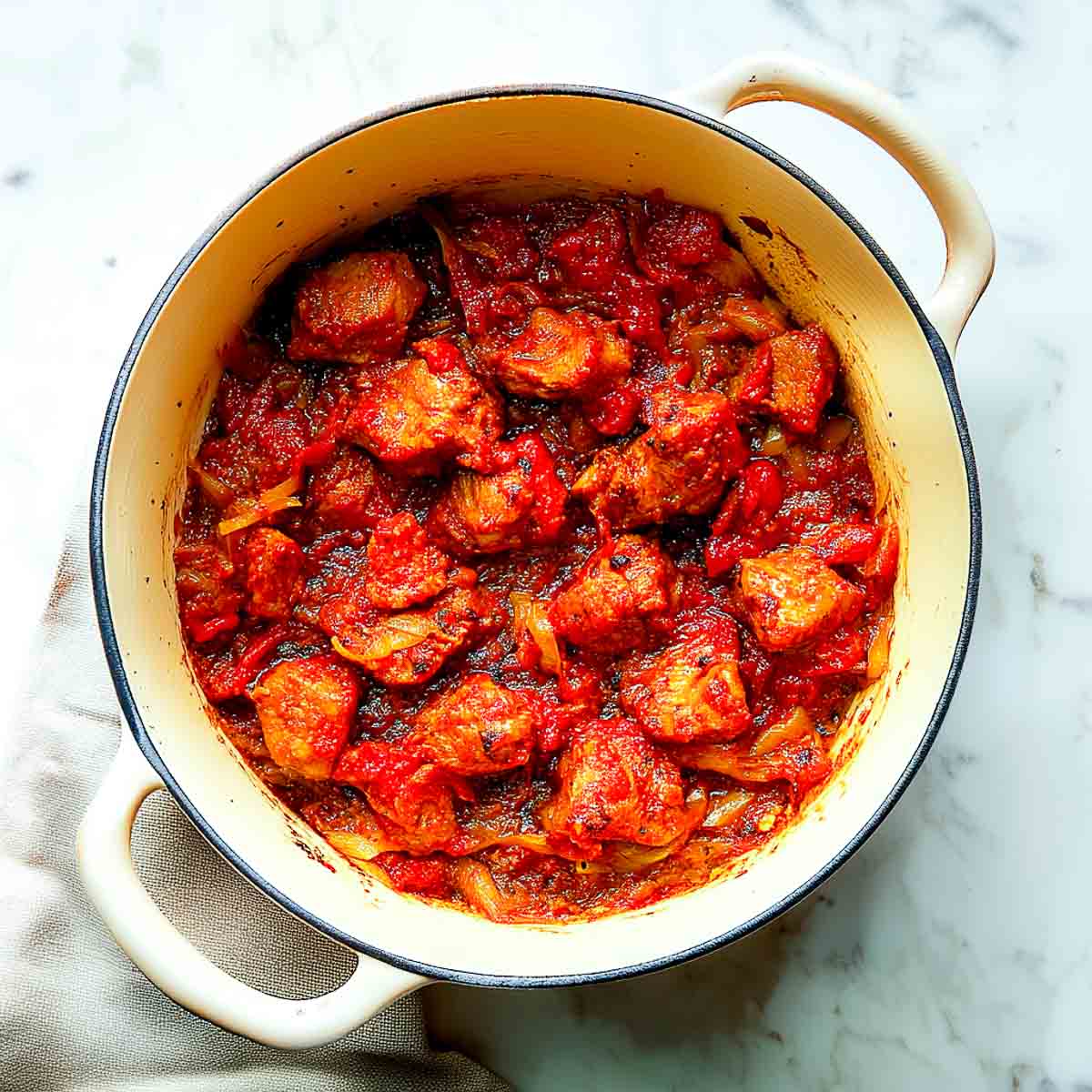 Lamb pieces coated in cooked tomato onion masala, frying until evenly browned.
