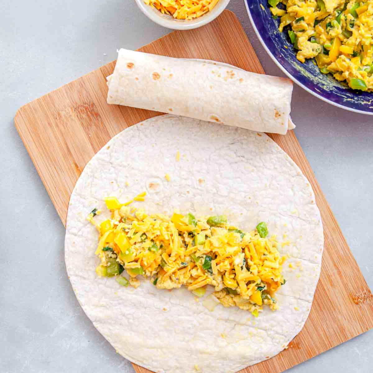 Filling added to tortilla while assembling homemade breakfast burritos.