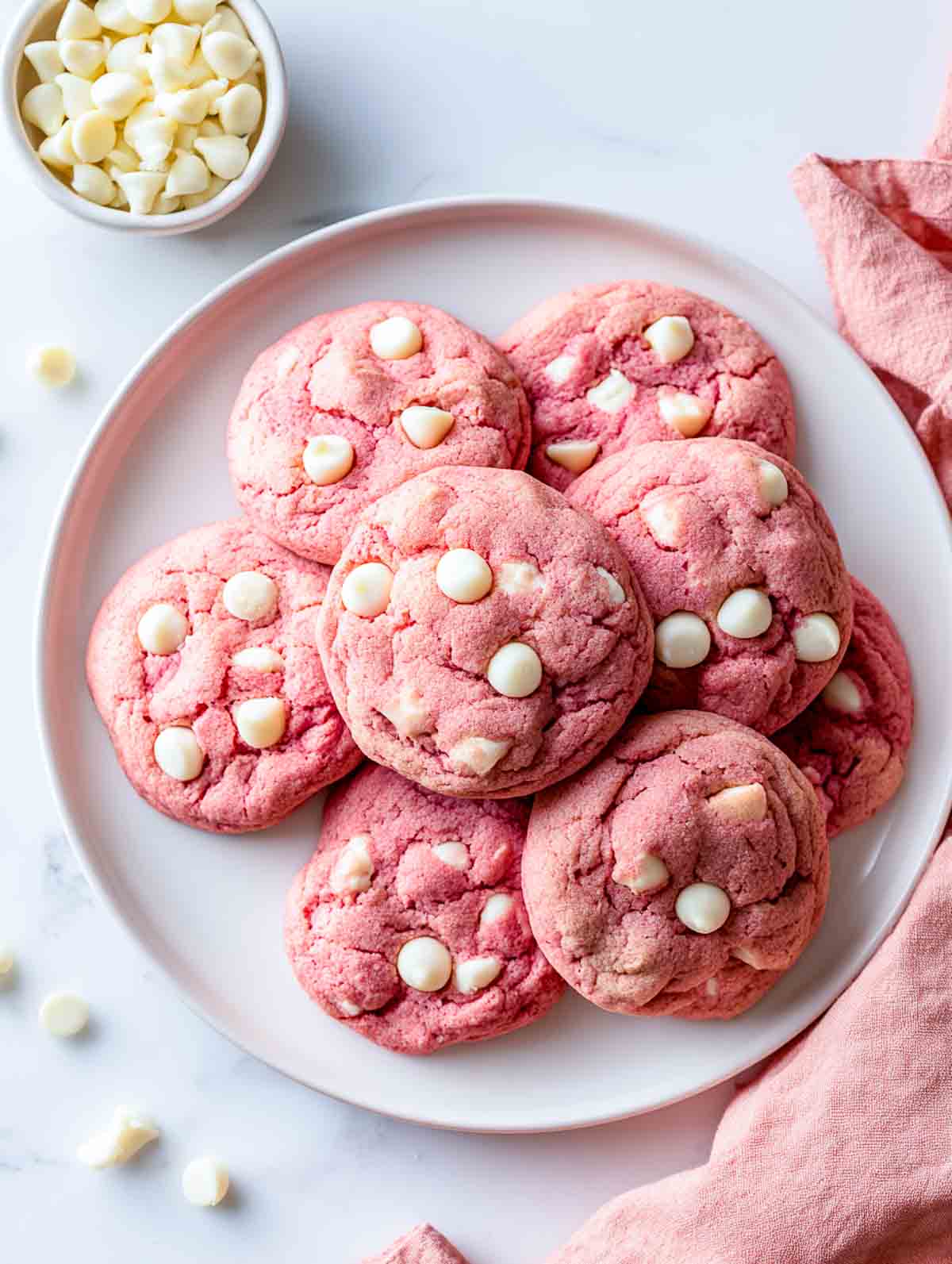 Pink velvet cookies with white chocolate chips on a white plate.