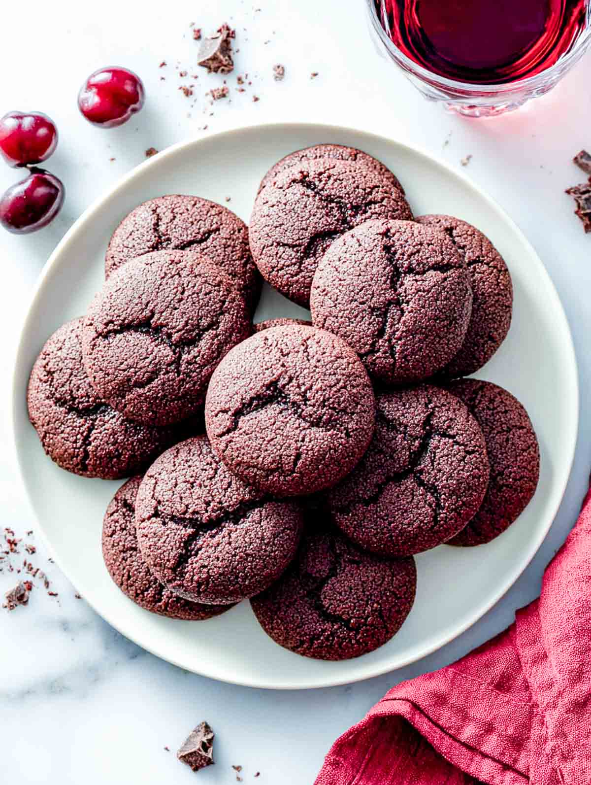 Red wine chocolate cookies on a white plate with a glass of red wine.