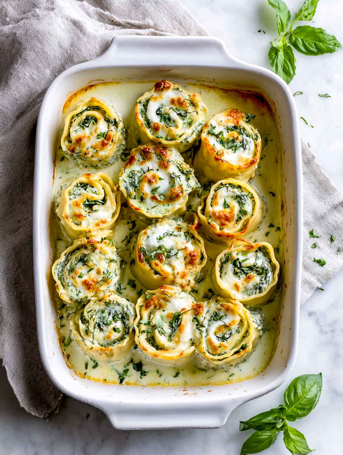 Upright spinach basil lasagna roll ups baked with melted mozzarella.
