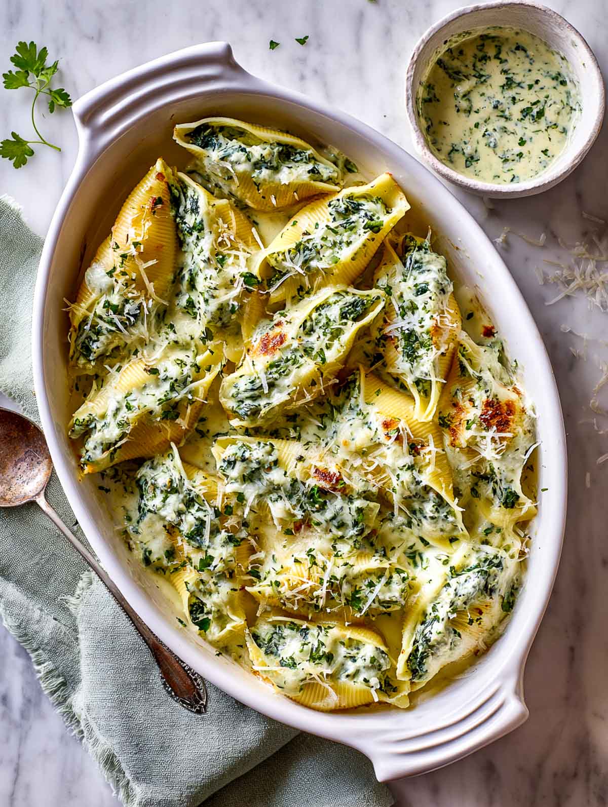 Baked spinach and ricotta stuffed shells nestled in a creamy herb sauce.