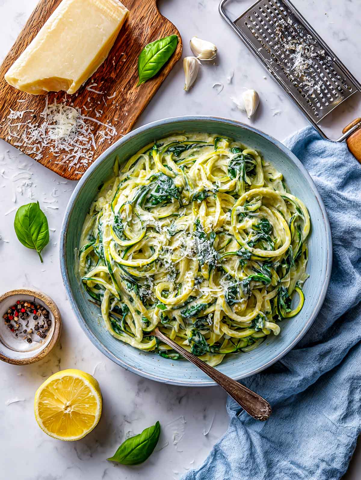 Zucchini noodles coated in a creamy spinach Alfredo sauce.