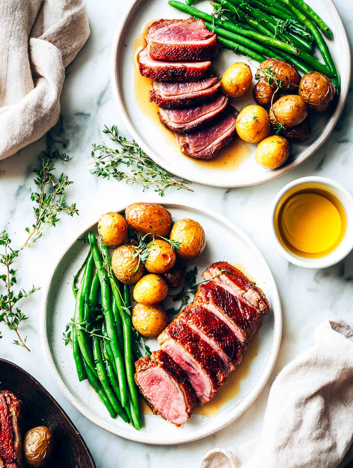 Plated duck breast with crispy skin, roasted potatoes, and green beans.