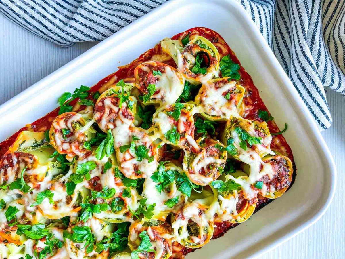 Baked spinach ricotta lasagna roll-ups with melted cheese and fresh parsley garnish