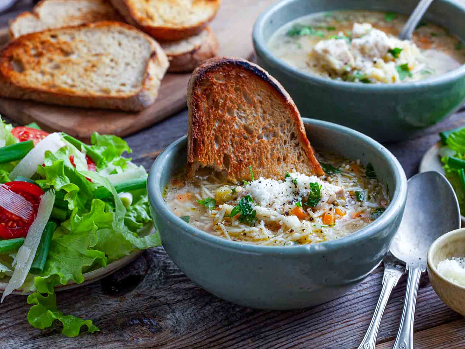 San Marino chicken fideo soup served in a bowl with golden toasted bread, fresh herbs, and a simple green salad on the side.