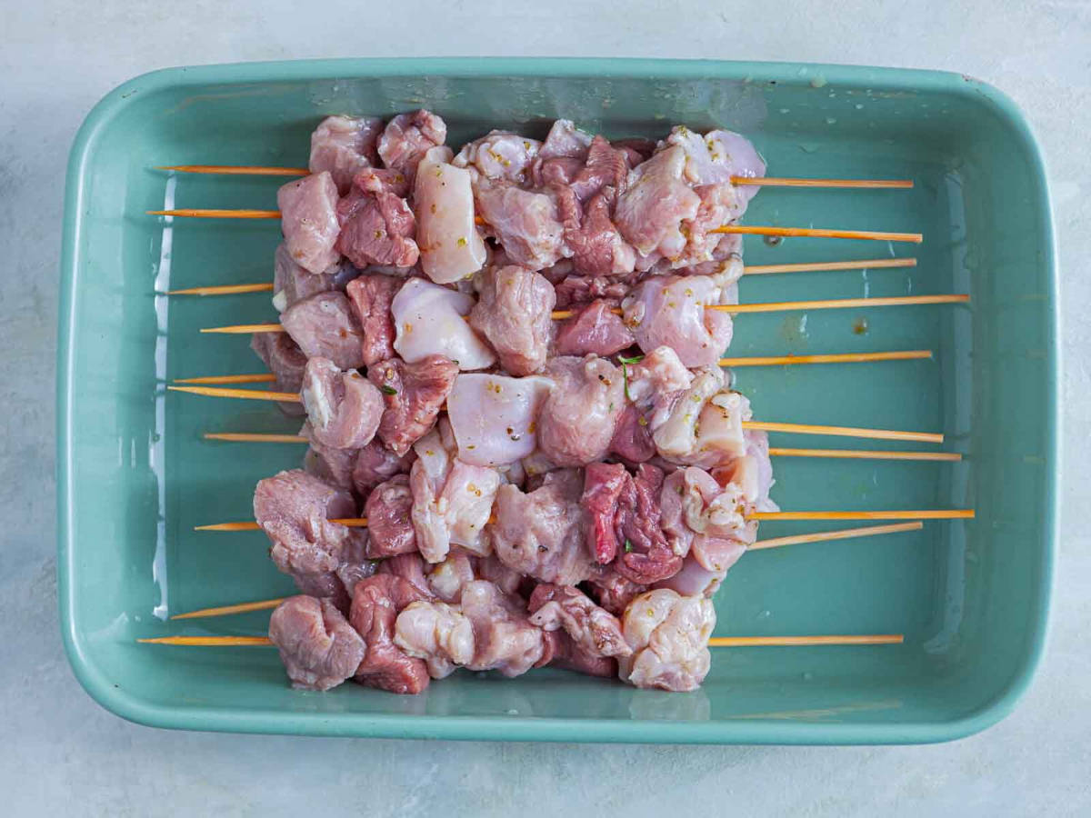 Skewers threaded with marinated chunks of raw meat, ready for grilling