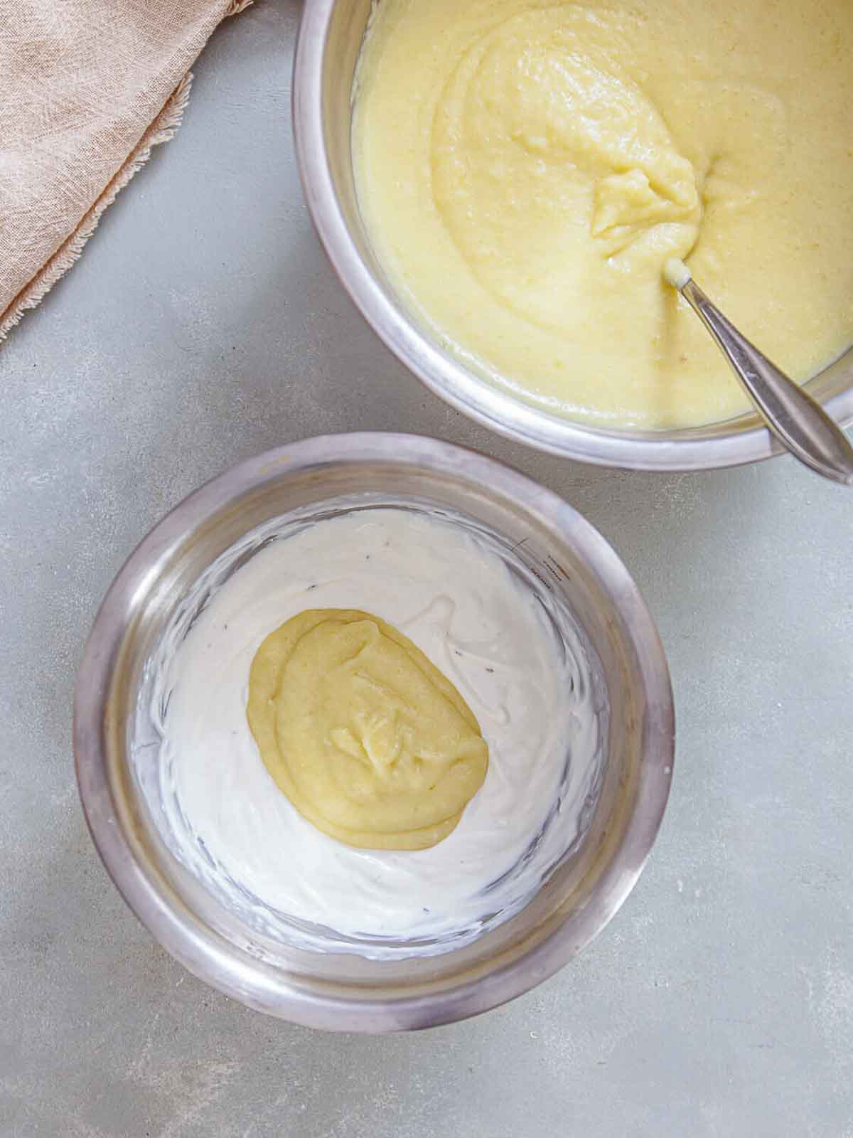 A bowl of thick, blended potato-leek mixture being added into a separate bowl of cream-showing the step where the soup base is combined with the creamy mixture to achieve a smooth, rich consistency