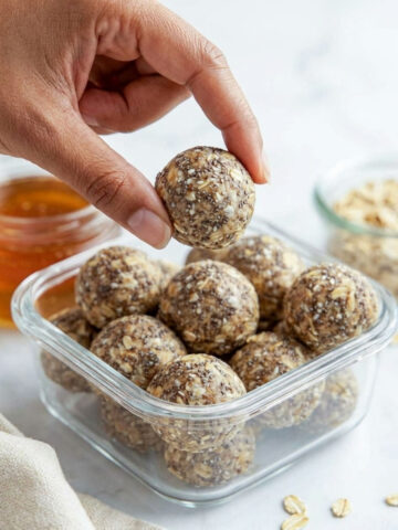 A hand picking up a protein energy ball made with oats, peanut butter, chia, and flaxseed