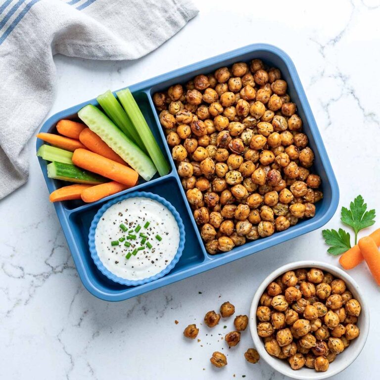 Crispy roasted chickpeas with ranch dip, cucumber, celery, and carrots in a blue lunchbox.