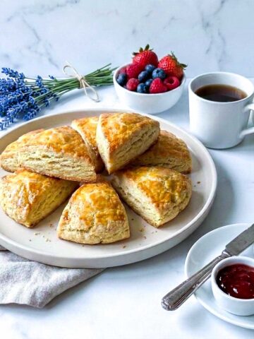 Kefir scones on a white plate with berries, coffee, butter, and jam.