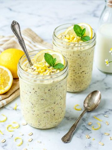 Lemon kefir overnight oats in glass jars topped with lemon zest, lemon slices, and mint.