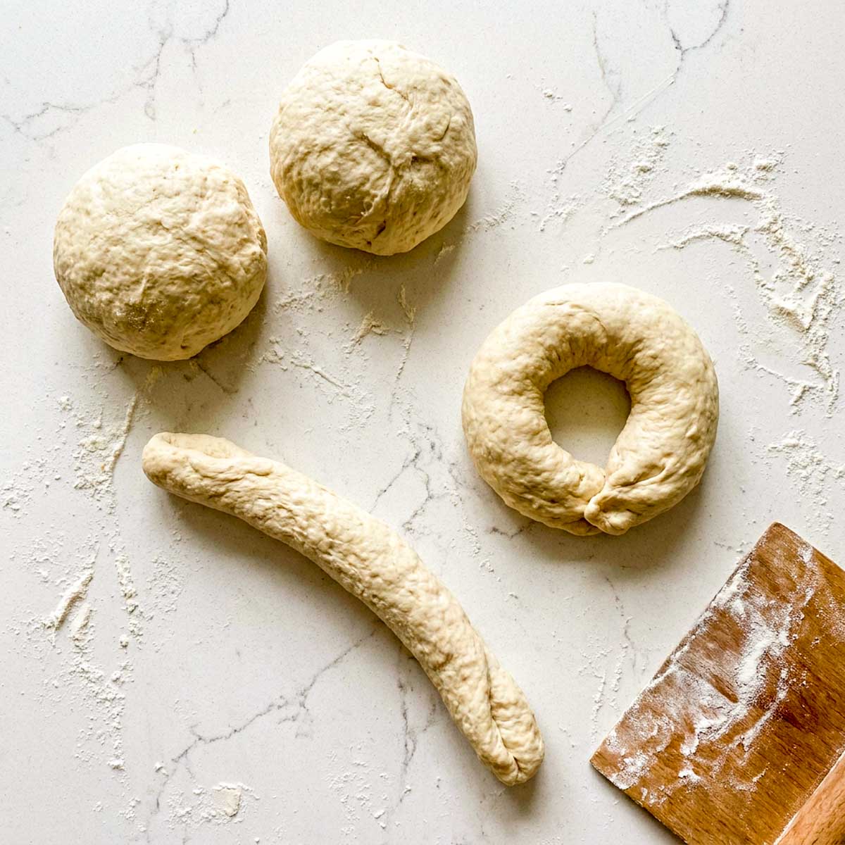 Cottage cheese bagel dough divided into balls, one rolled into a rope and one shaped into a ring.