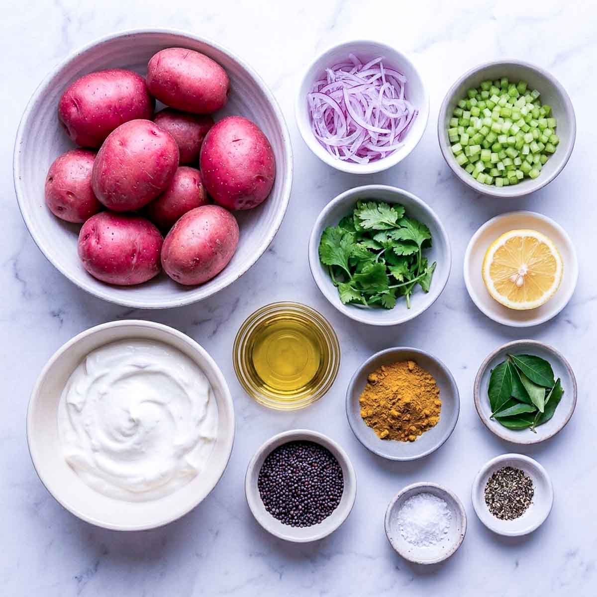 Ingredients for curry potato salad including red potatoes, yogurt, curry powder, mustard seeds, curry leaves, red onion, celery, cilantro, and lemon.