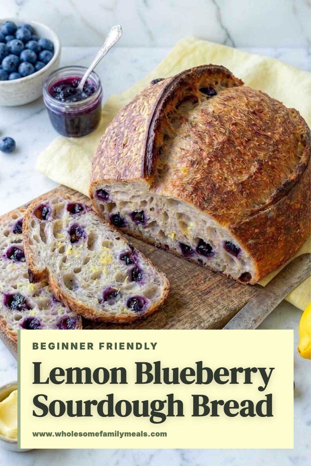 A sliced lemon blueberry sourdough loaf on a light marble counter in soft daylight.