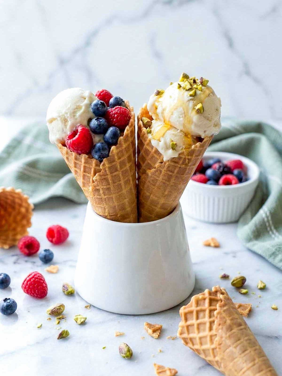 Kefir ice cream in waffle cones with fresh berries, chopped pistachios and a honey drizzle.