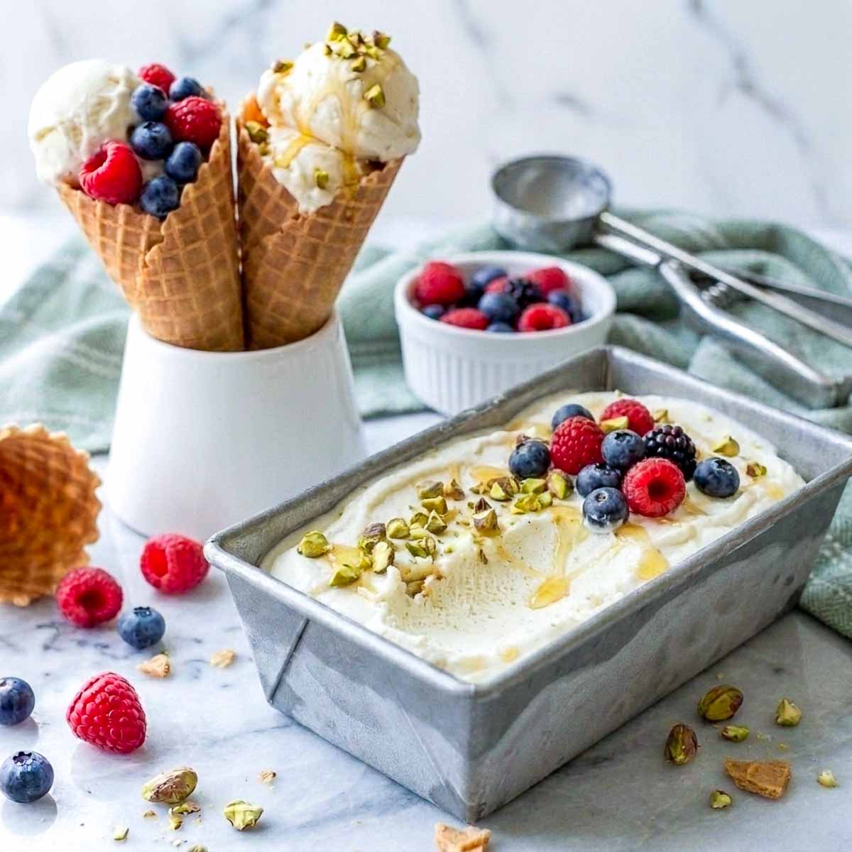 No churn kefir ice cream frozen in a metal loaf pan, topped with berries, pistachios and honey.