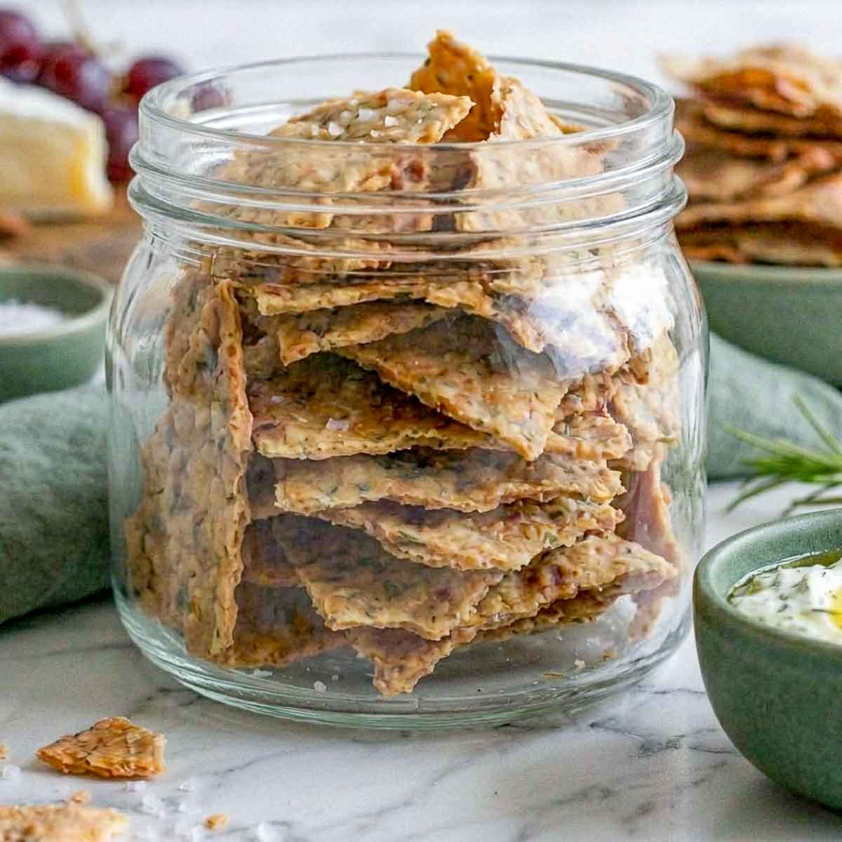 Sourdough discard crackers stacked in a glass storage jar.
