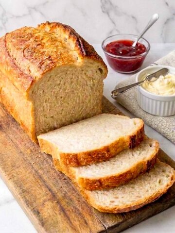 Sourdough sandwich bread sliced on a board with butter and jam.