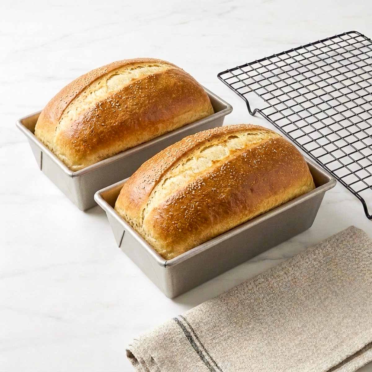 our step collage showing risen sourdough dough, dividing it in two, rolling it into a log, and proofing in two loaf pans.