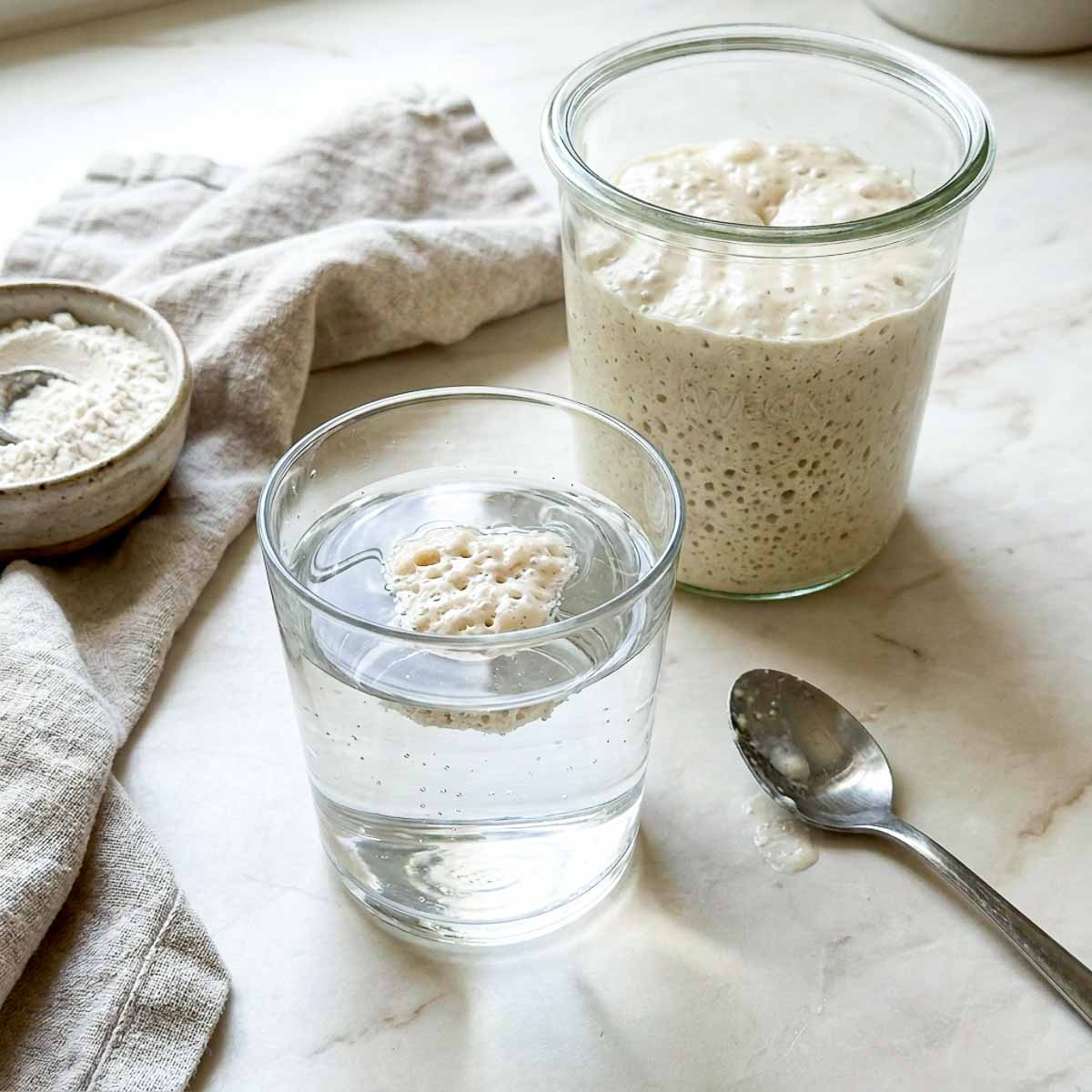 Spoonful of sourdough starter floating in a glass of water during the float test.