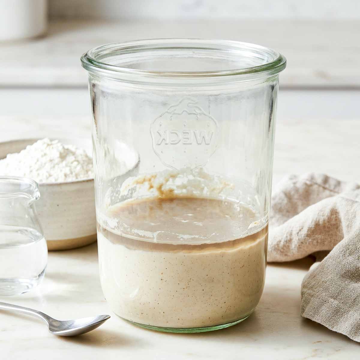 Dark hooch liquid on top of a sourdough starter in a glass jar.