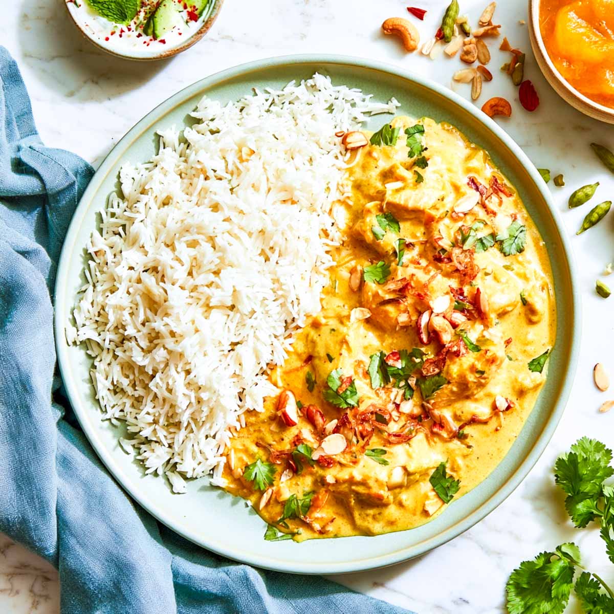 Plate of easy creamy chicken korma served with steamed basmati rice and a cucumber raita.