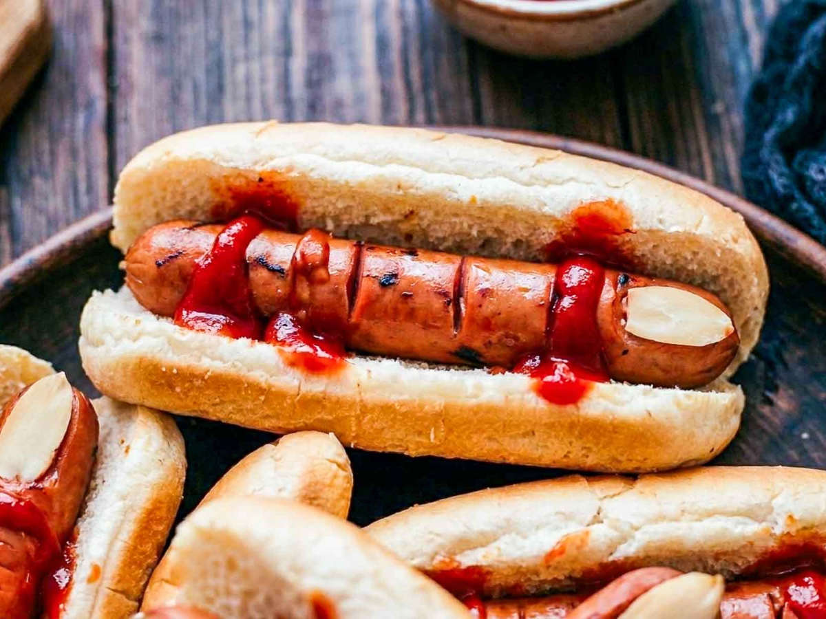 Close up of one Halloween hot dog finger in a bun showing the almond nail and open knuckle cuts.