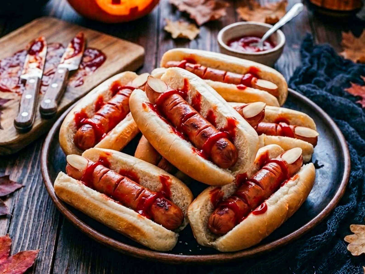 Side view of Halloween hot dogs served on a rustic plate.