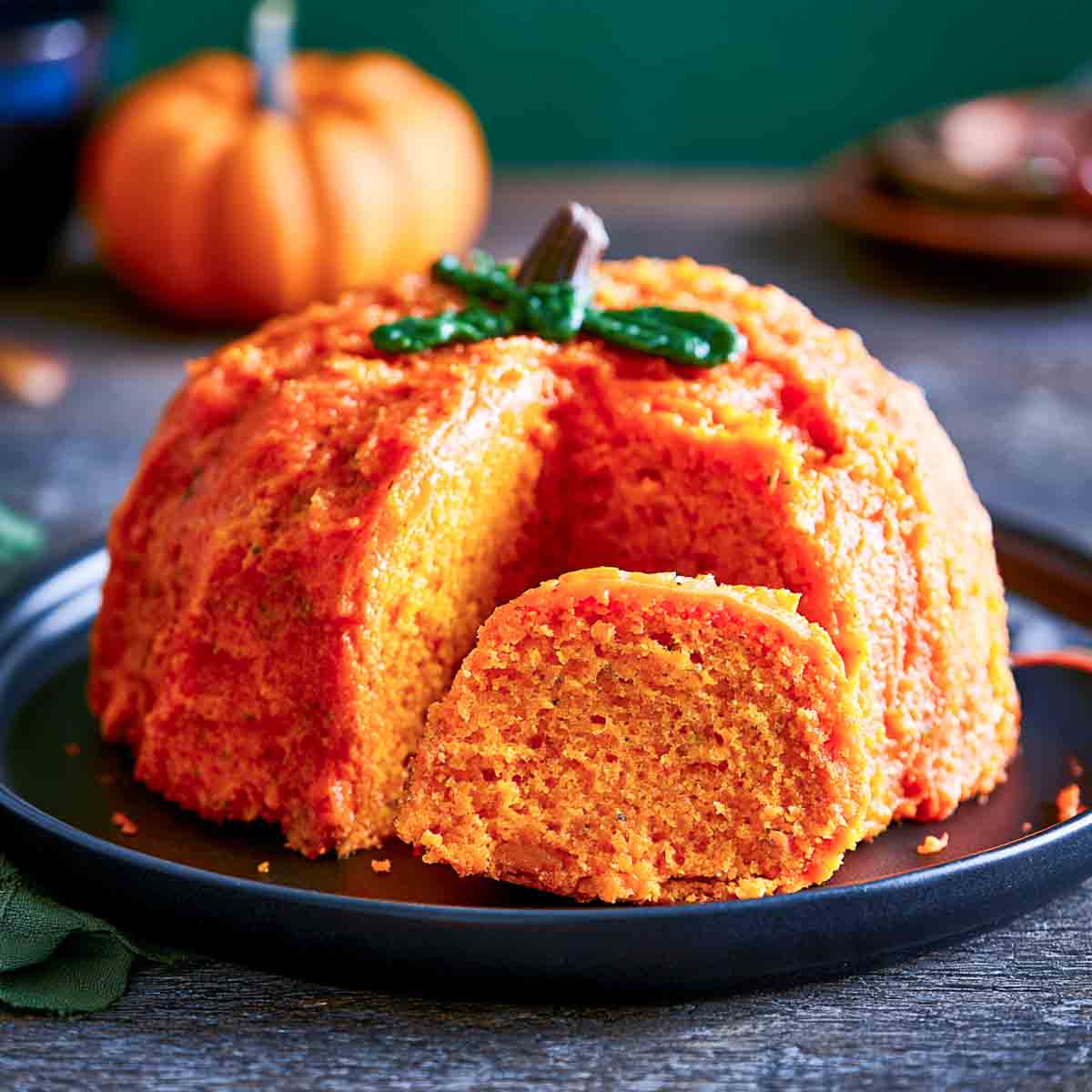 Pumpkin spice Bundt cake topped with creamy coffee-colored glaze and a dusting of cinnamon, served on a ceramic plate.