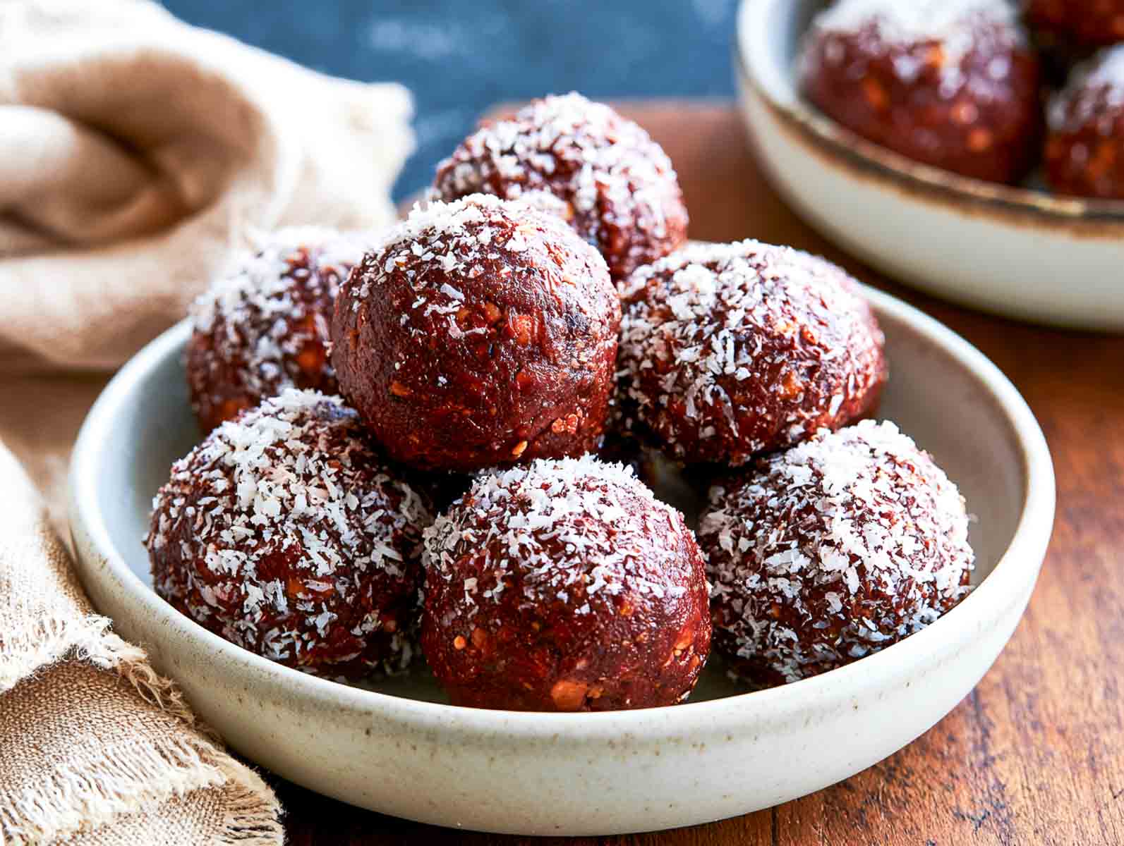 Vegan chocolate coconut high-protein energy balls rolled in shredded coconut in a ceramic bowl.