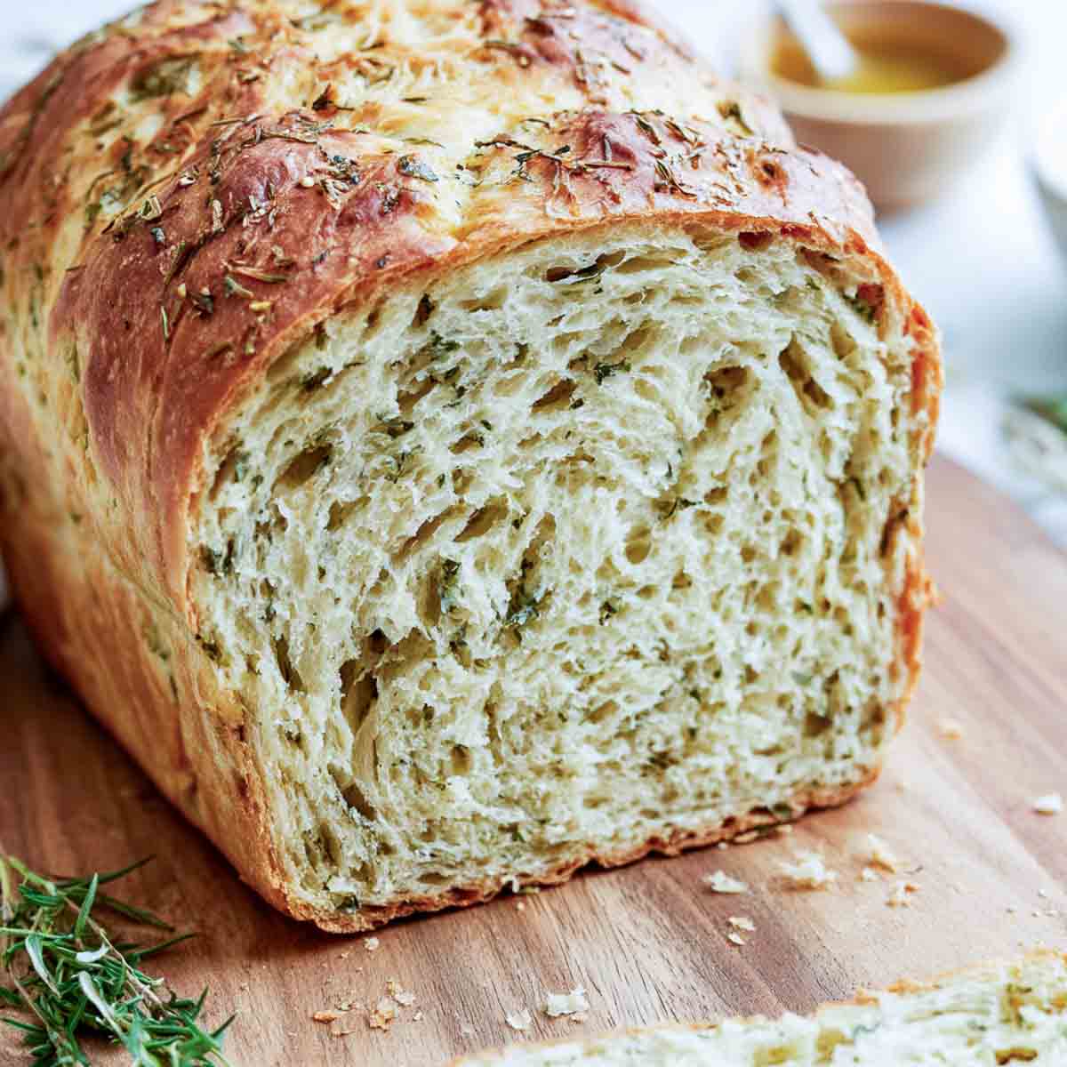 Close-up of the soft interior crumb of kefir bread flecked with rosemary, thyme, and parsley.