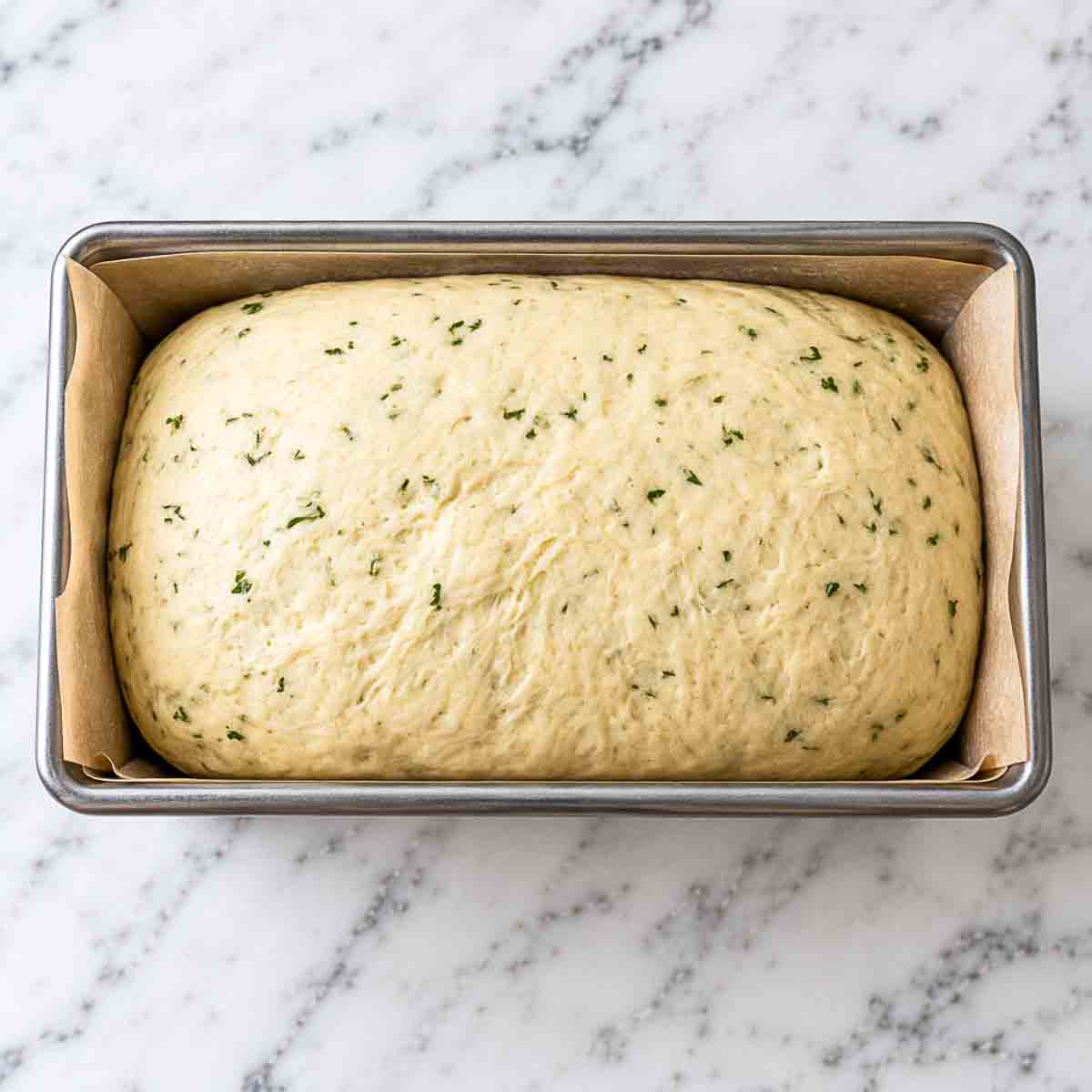 Shaped kefir bread dough resting in a parchment-lined loaf pan before the second rise.