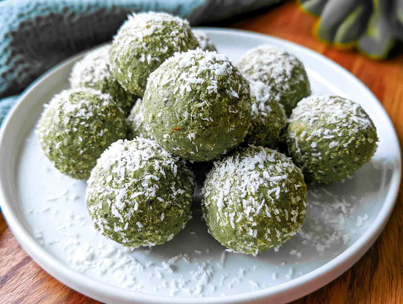 Green matcha coconut high-protein energy balls rolled in shredded coconut on a white plate.