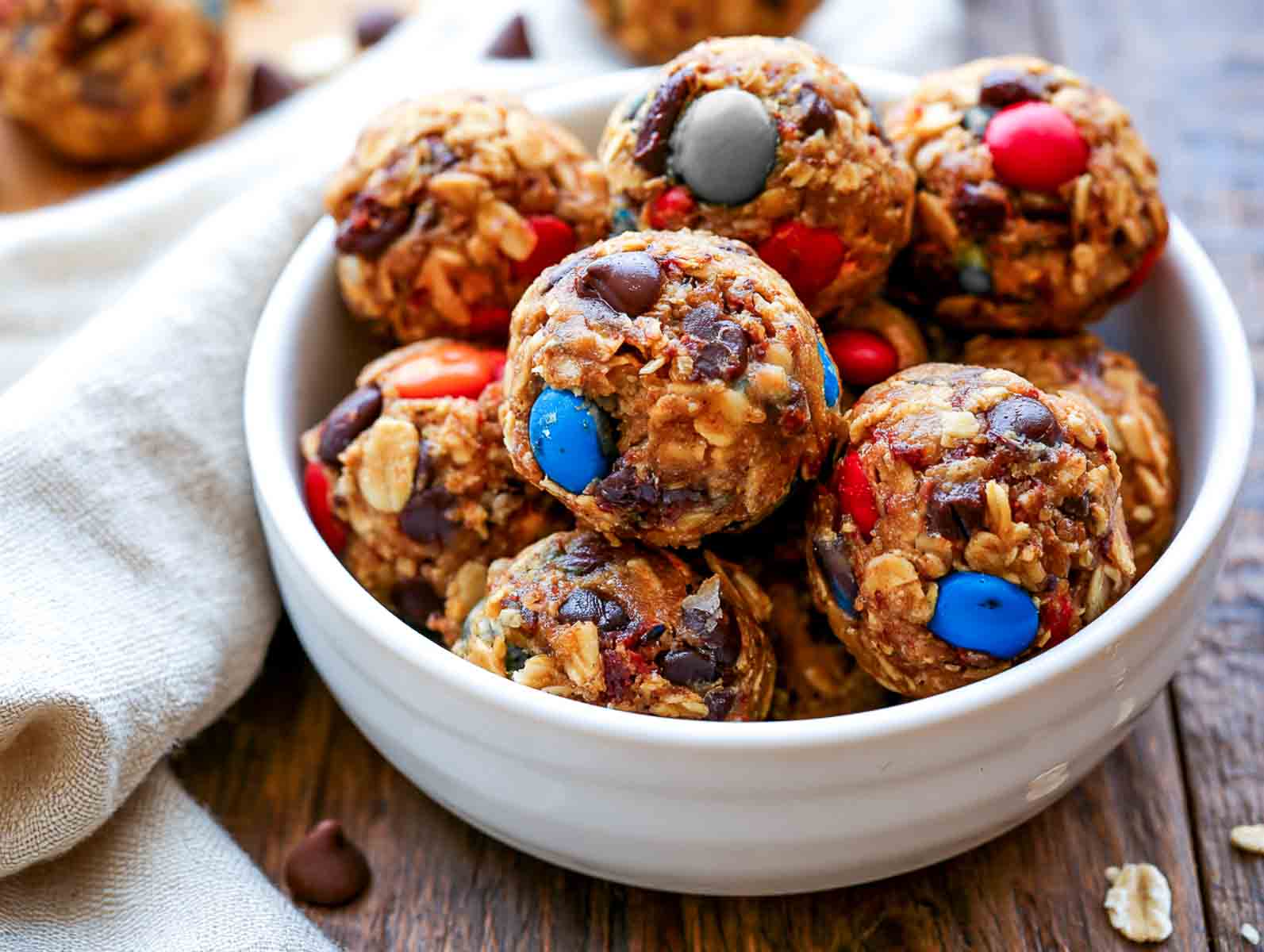 Monster cookie high-protein energy balls with rolled oats, colorful candy-coated chocolates, and chocolate chips in a white bowl.