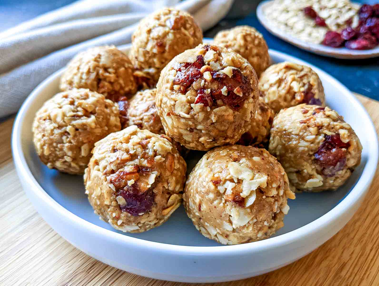 Peanut butter oatmeal high-protein energy balls with rolled oats and mini chocolate chips on a plate, with chocolate chips, bananas, and oats nearby.