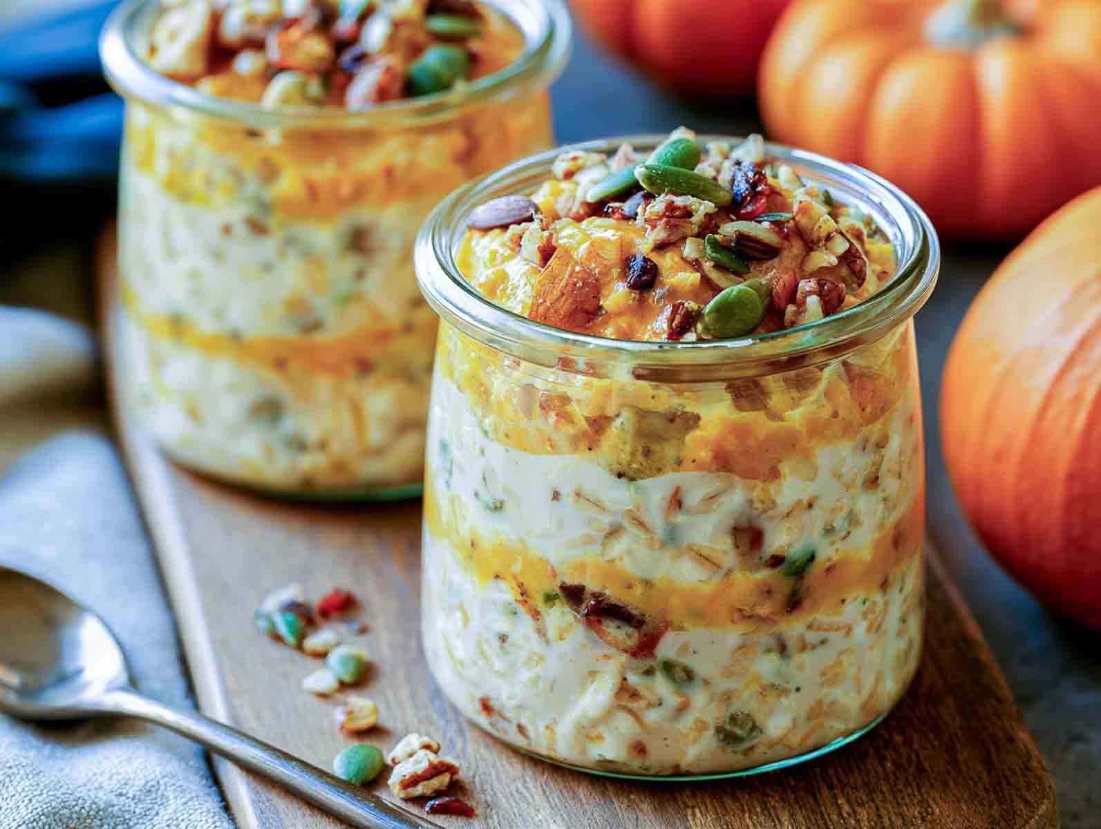 Layered pumpkin kefir overnight oats topped with pumpkin seeds, pecans, and dried cranberries.