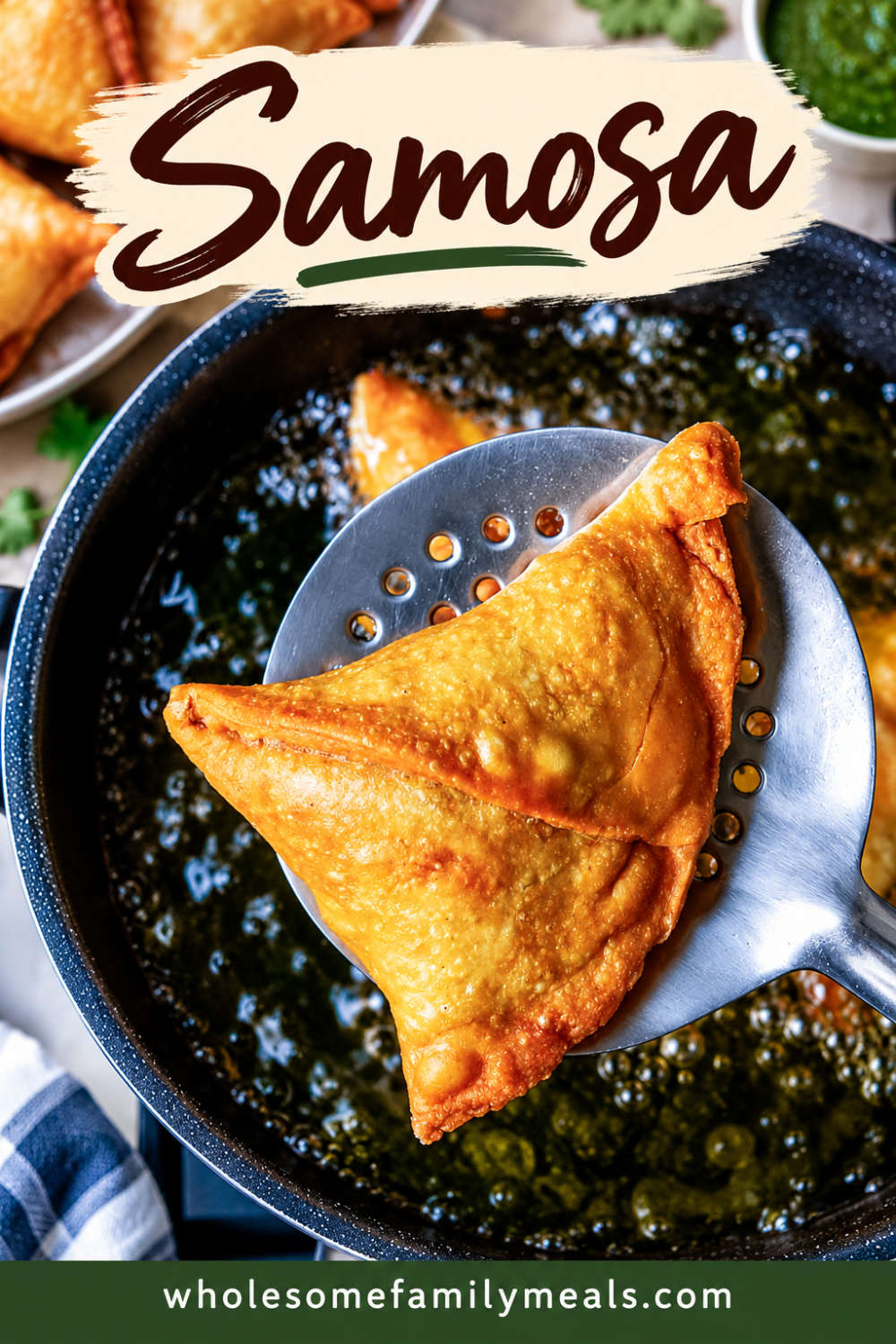 A golden fried samosa lifted out of hot oil on a slotted spoon with more samosas on a plate behind it.