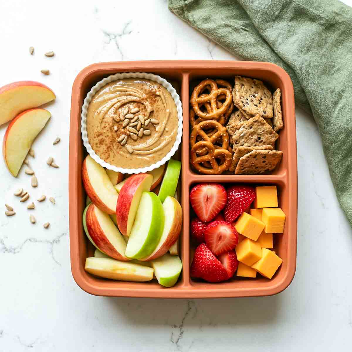 SunButter apple dippers with sliced apples, pretzels, whole-grain crackers, strawberries, and cheese cubes.